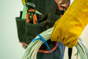 Elektriker mit Kabelrolle in der Hand und Werkzeug in den Gürrteltaschen